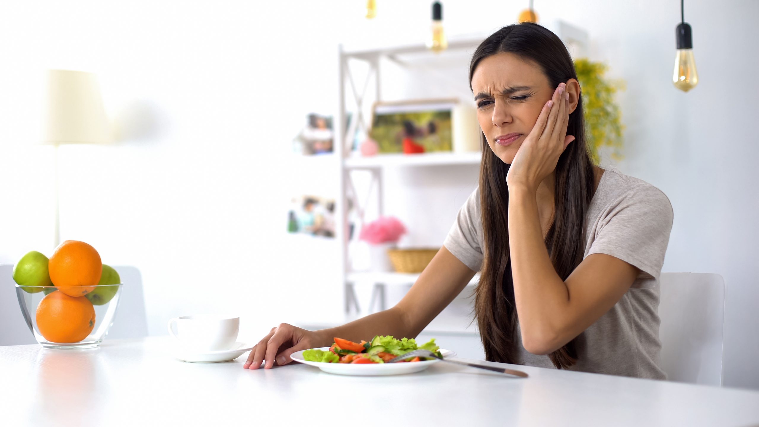 A woman wonders what to eat after a tooth extraction, as crunchy foods cause her pain.